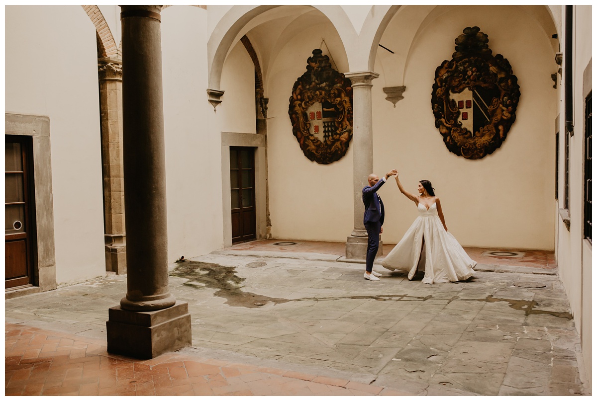 couple dancing in courtyard at italian wedding venue. bride is wearing eco friendly, timeless, wedding dress in ballgown style available in half sizes ensuring the perfect fit