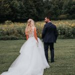 Groom turns around to see bride in her sleeveless wedding dress for the first look.