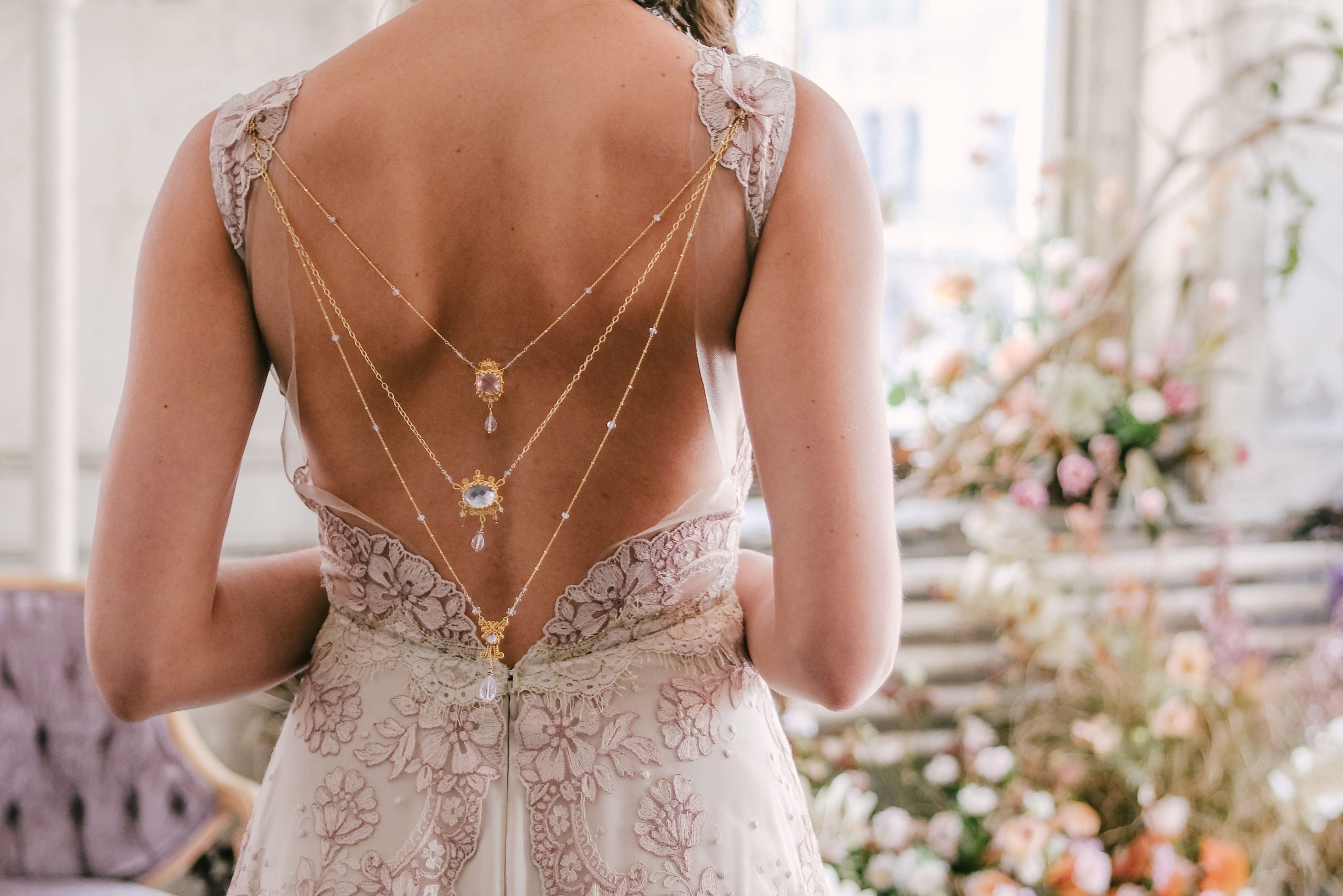 Close up of a statement open back dress with necklacke-style chains draping down the back from the shoulder straps