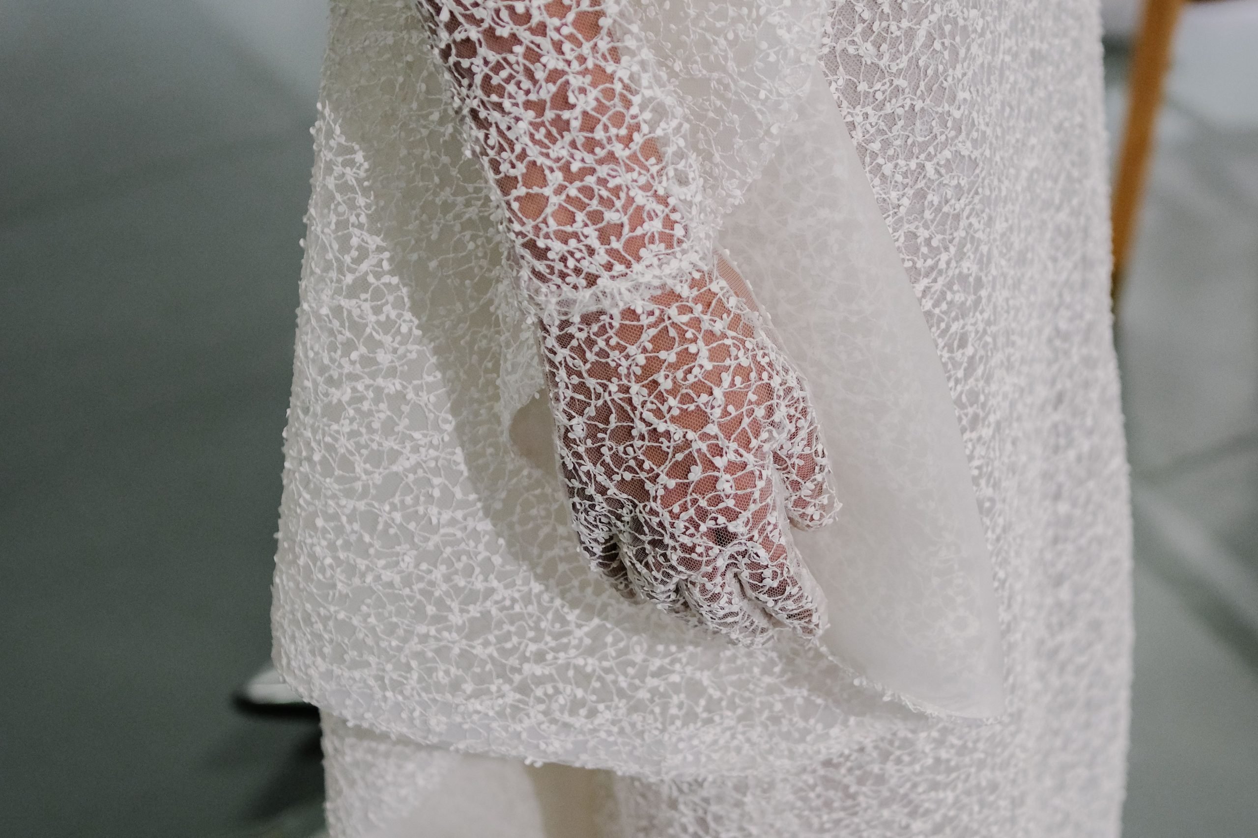 Close of detail shot of the intricate see-through lace pattern of a hand in Francesca Miranda bridal gloves paired with a matching dress